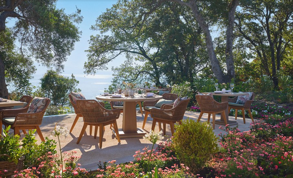 Ikos Odisia Korfu – Restaurant-Terrasse im blühenden Garten mit Meerblick und gedeckten Tischen