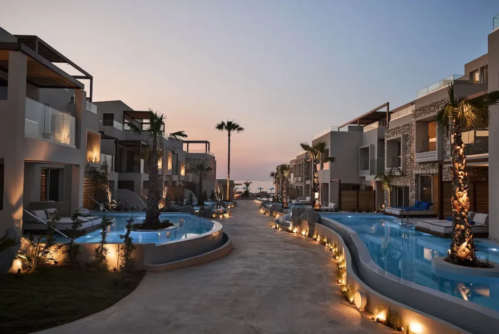 Beleuchtete Poolanlage zwischen modernen Suiten im UZENIE All Suites Boutique Resort auf Kreta bei Sonnenuntergang