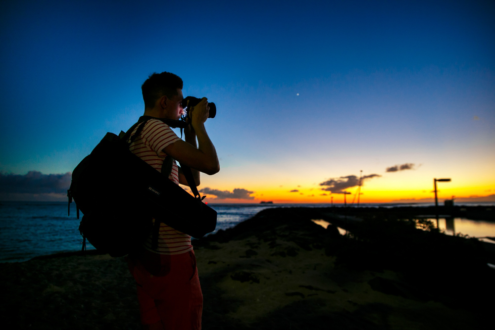 Mann mit Kamera und Rucksack am Strand