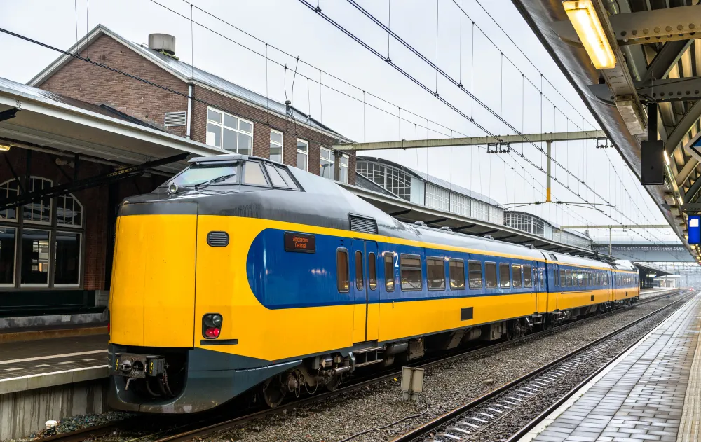 Gelb-blauer niederländischer Zug am Bahnhof als Symbolbild für das Holland Ticket Nederland Dal Vrij für 49 € pro Monat im Sommer 2026